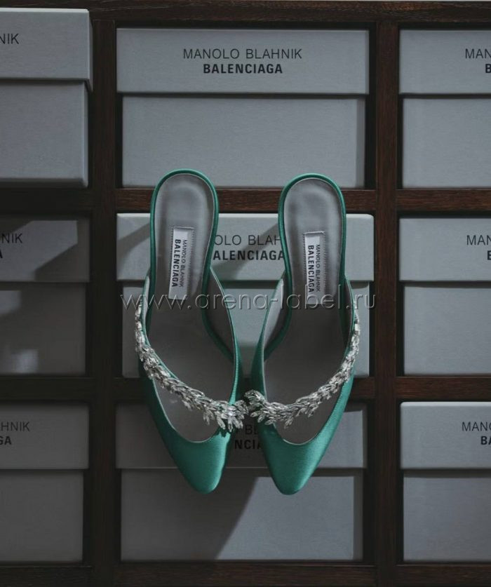 Атласные туфли Balenciaga x Manolo Blahnik с декоративной серебристой отделкой на фоне фирменных коробок.